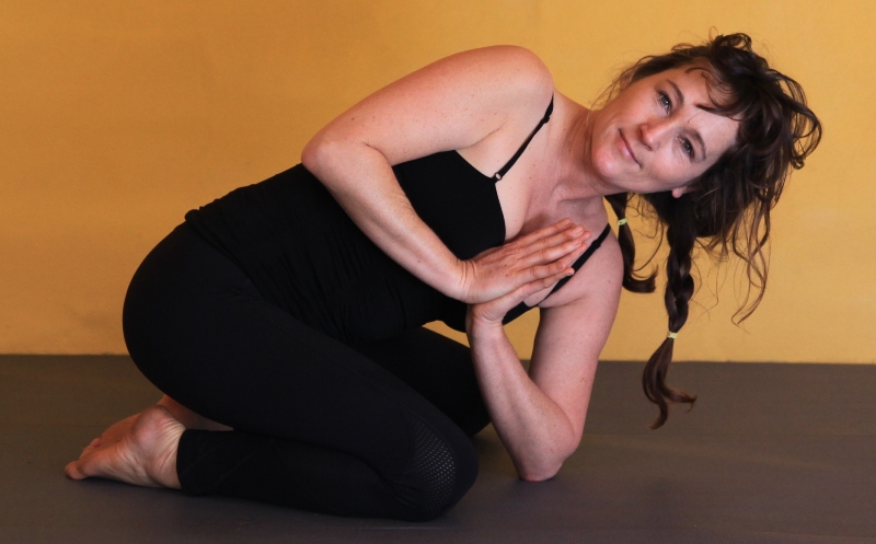 Woman doing yoga twist pose on floor.