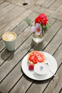 Coffee, strawberry tart, flowers on wooden table.