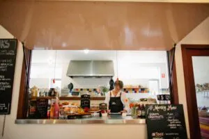 Cafe kitchen with menu boards and food display.