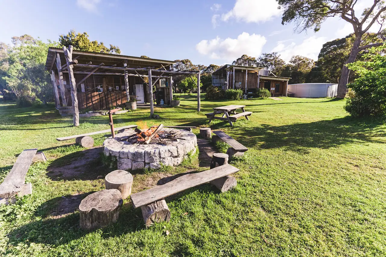 Rustic outdoor campsite with fire pit and benches.