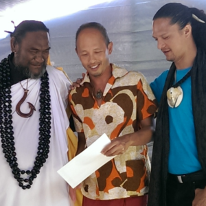 Three men talking and holding a paper together.