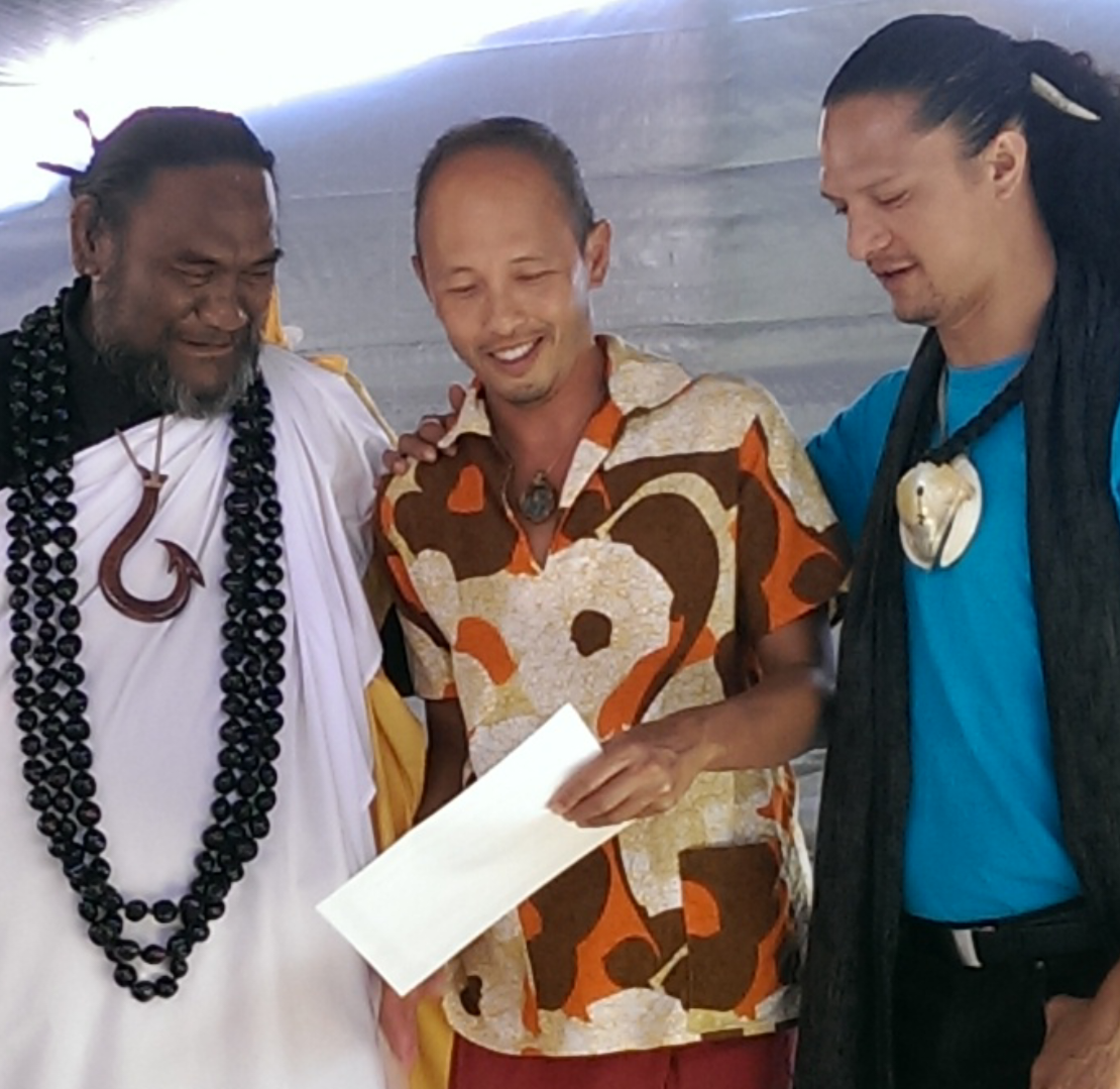 Three men talking and holding a paper together.